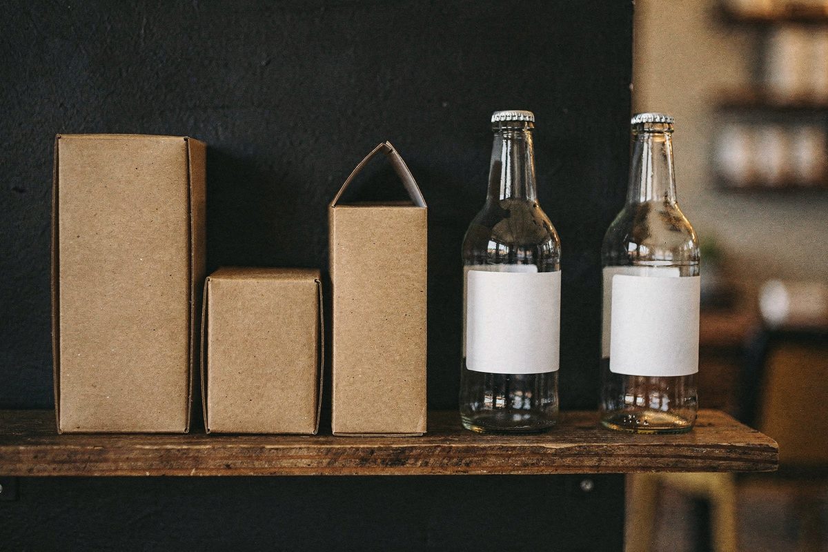 Finished kraft cartons and glass bottles with blank labels arranged on a shelf